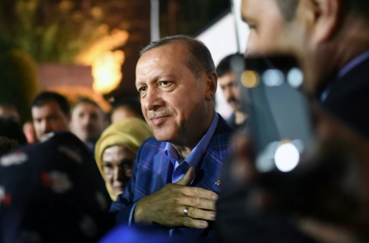 Le président Erdogan (c), accompagné de sa femme Emine, salue ses supporters en sortant du siège du parti AKP, le 16 avril 2017 à Istanbul