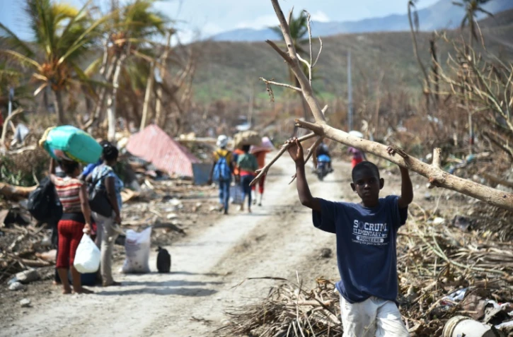 Des Haïtiens dans une rue dévastée après le passage de l'ouragan Matthew le 10 octobre 2016 à Les Cayes