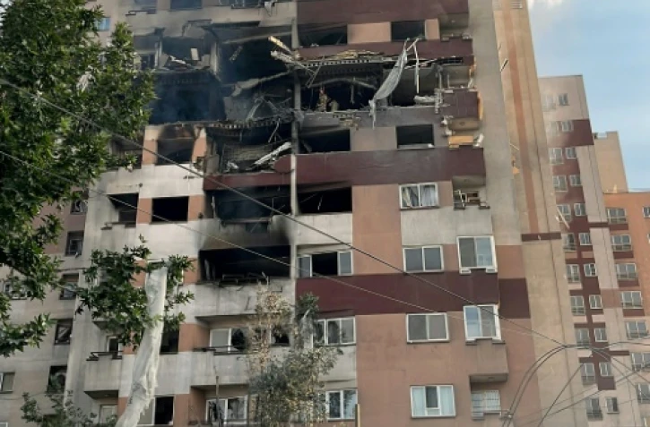 Des passants sont rassemblés devant un bâtiment visé par une frappe israélienne dans la capitale iranienne, Téhéran, le 13 juin 2025