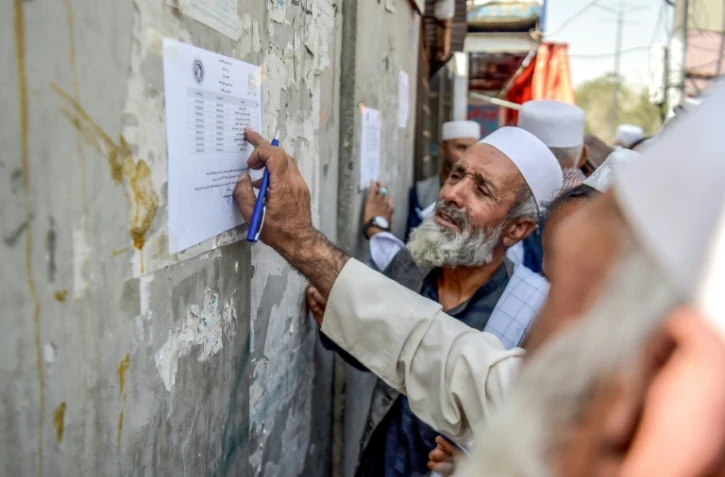 Un retraité vérifie une liste devant un bâtiment gouvernemental à Kabou, le 25 août 2025 en Afghanistan