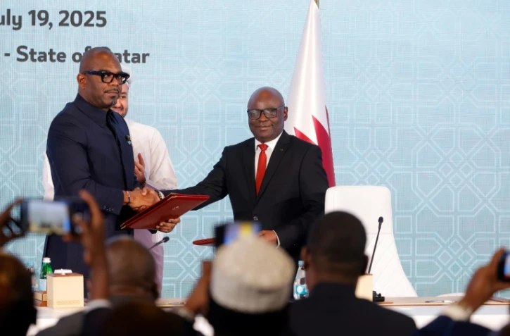 Le chef de la délégation congolaise Sumbu Sita Mambu (G) serre la main du secrétaire exécutif du groupe armé M23,  Benjamin Mbonimpa (D), après avoir signé une déclaration de principe comprenant un accord de cessez-le-feu, le 19 juillet 2025 à Doha