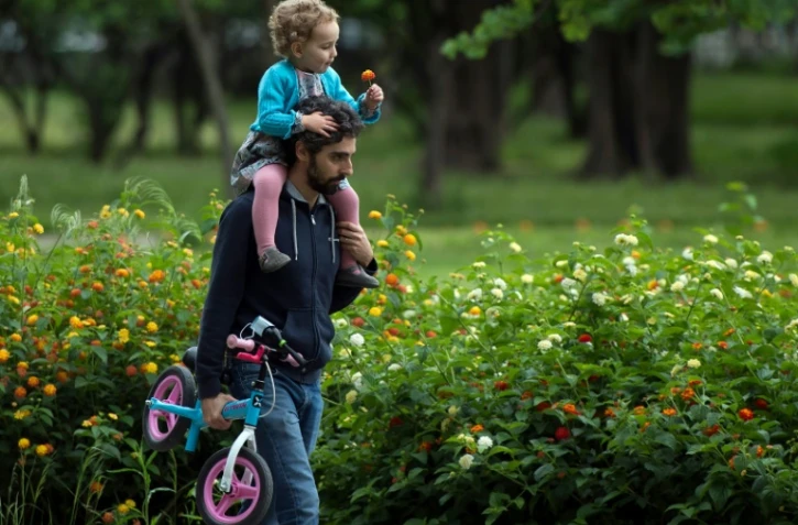 Un homme porte sa petite fille sur les épaules dans un parc à Séville, en Espagne, le 26 avril 2020