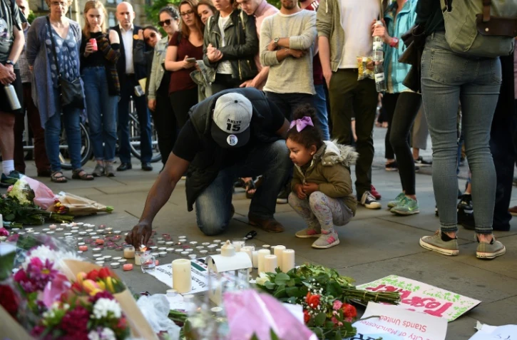 Un homme et sa petite fille allument des bougies Ă quelques pas du lieu de l'attentat Ă l'Albert Square de Manchester le 23 mai 2017