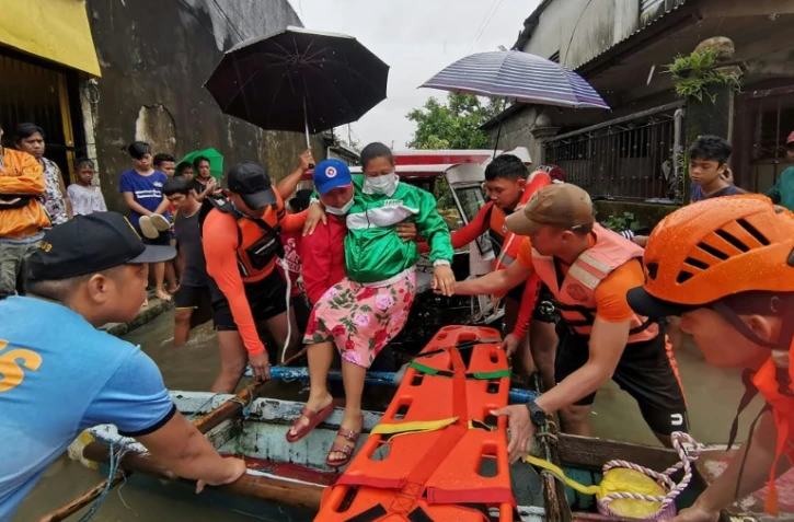 Photo non datée diffusée le 11 avril 2022 par les gardes-côtes philippins d'une habitante évacuée d'une zone inondée après le passage de la tempête Megi, le 11 avril 2022 à Abuyog, dans la province de Leyte