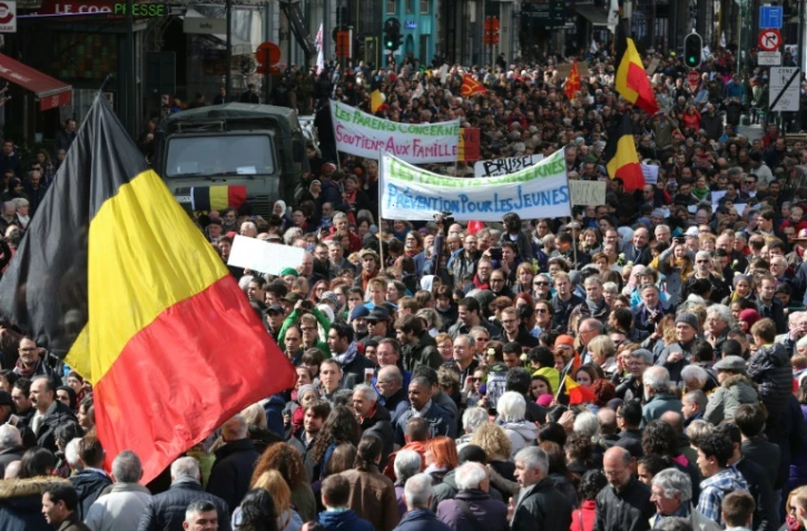 Le drapeau national belge et des pancartes lors de la marche pacifique contre le terrorisme à Bruxelles le 17 avril 2016
