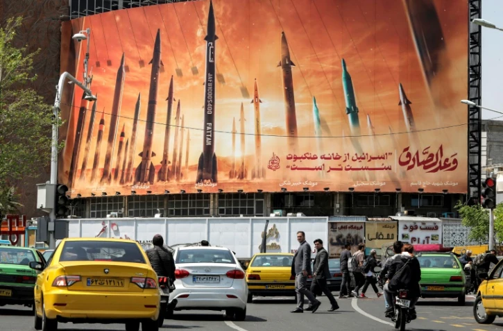 Des automobilistes passent devant un panneau d'affichage représentant des missiles balistiques iraniens, dans le centre de Téhéran, le 15 avril 2024