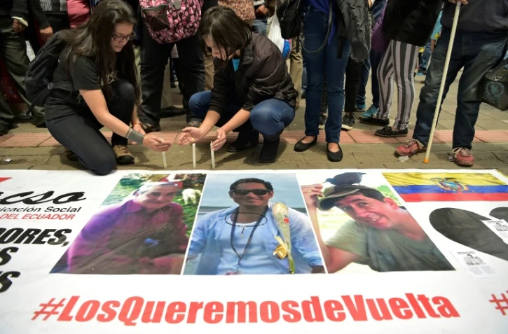 Des proches des deux journalistes équatoriens Javier Ortega et Paul Rivas et de leur chauffeur Efrain Segarra, alument des bougies près de leurs portraits après l'annonce de leur mort, le 13 avril 2018 à Quito