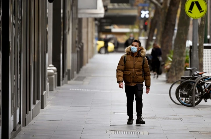 Un homme portant un masque descend Collins Street, dans un quartier commercial normalement bondé de Melbourne, dans l'Etat de Victoria, où ont été recensés la plupart des 502 nouveaux cas de coronavirus annoncés mercredi par l'Australie