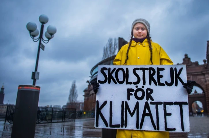 Greta Thunberg tient une pancarte indiquant "Grève scolaire pour le climat", face au Parlement suédois, le 30 novembre 2018 à Stockholm