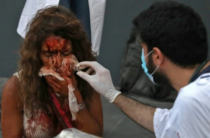 Un médecin soigne une femme devant un hôpital le 4 août 2020 après deux énormes explosions à Beyrouth