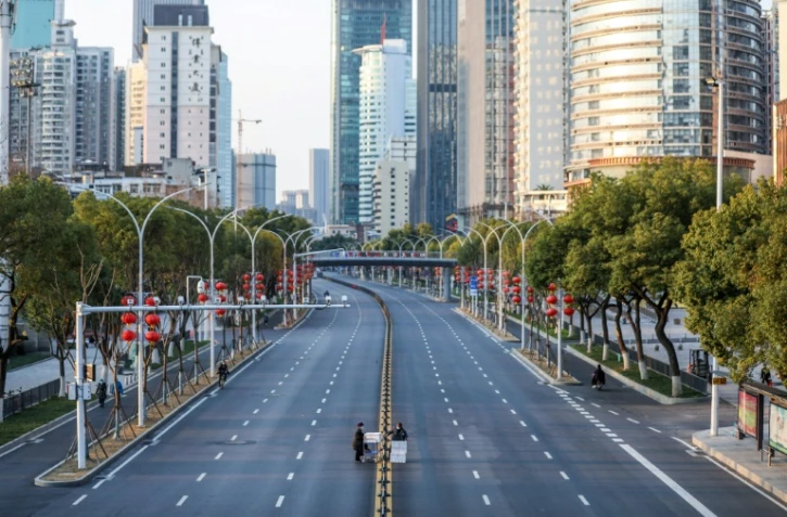 Des personnes traversent des routes désertées par les automobilistes le 20 février 2020 à Wuhan, épicentre initial en Chine