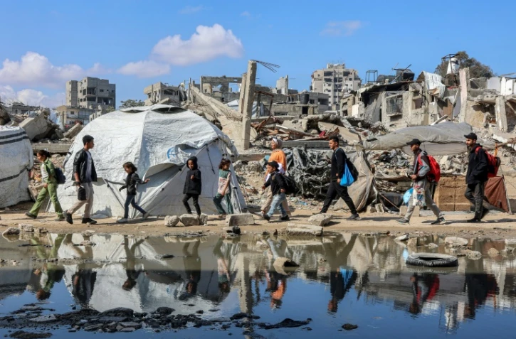 Des palestiniens marchent près des décombres d'un bâtiment effondré dans le quartier de Nasr, à l'ouest de la ville de Gaza, le 15 avril 2025