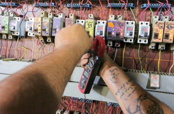 L'Irakien Aqeel Hassan, l'un des propriétaires de générateurs électriques privés, le 17 juillet 2021 en train de réparer les interrupteurs de son entreprise dans le quartier de Sadr City à Bagdad, qui alimente 270 foyers dans le quartier quand le réseau national défaillant tombe en panne