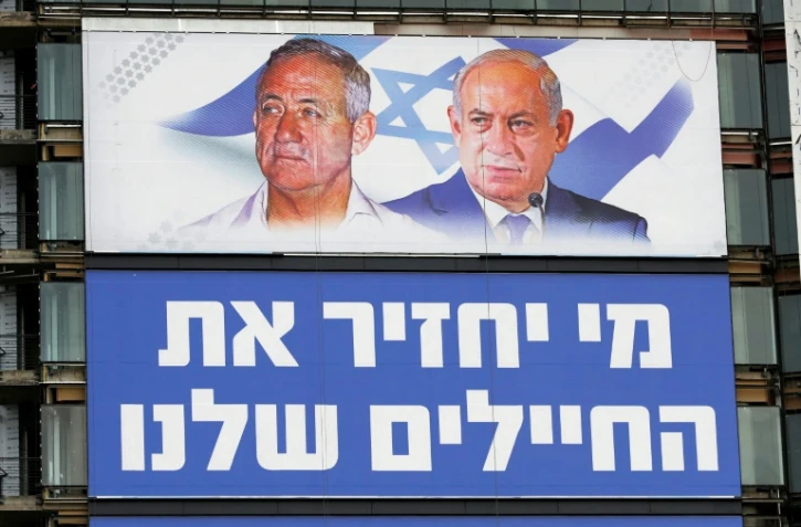 Une affiche électorale montre à Tel-Aviv le 29 mars 2019 les portraits du général Benny Gantz (à gauche) et du Premier ministre Benjamin Netanyahu (à droite), rivaux pour les prochaines élections législatives, tandis qu'en-dessous est inscrit "Qui ramènera nos soldats?"