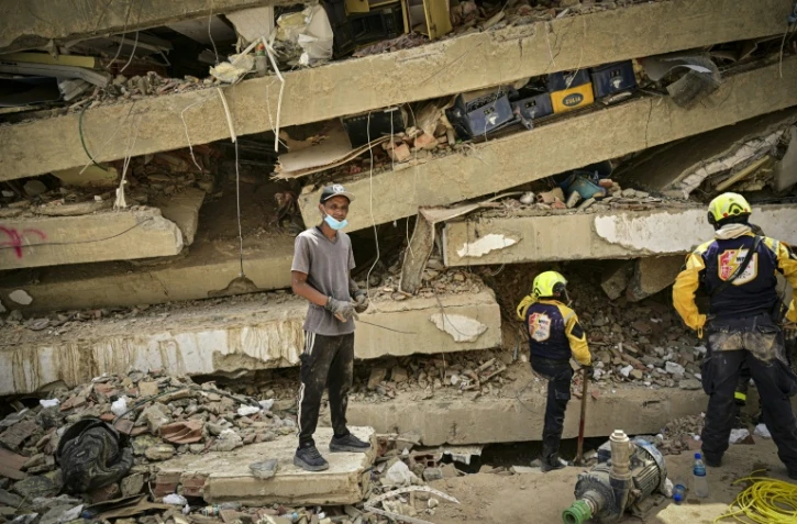 Raul Alvarado (g) cherche des proches disparus sous les décombres de l'immeuble OPP 26 de 16 étages ç Carabellada, dans l'Etat de La Guaira, le 6 juillet 2026 au Venezuela