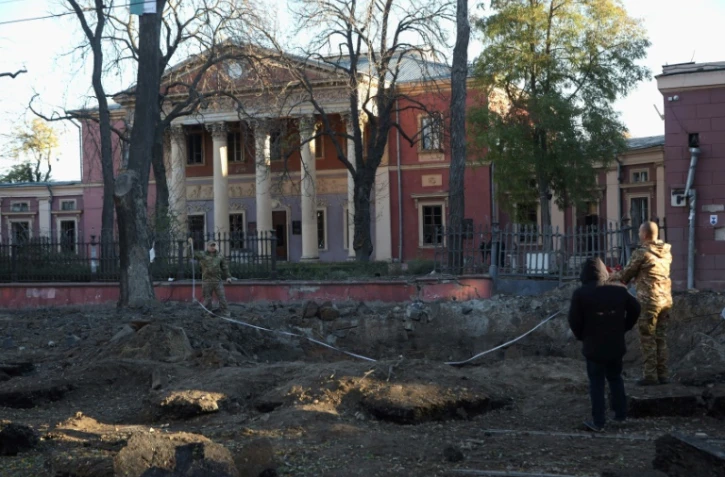 Des experts de la police mesurent un cratère devant le musée des Beaux-Arts d'Odessa, après une frappe la veille, le 6 novembre 2023 en Ukraine