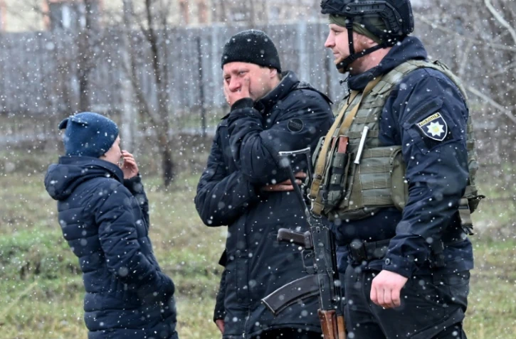 Des personnes se tiennent près d'une fosse commune dans la localité ukrainienne de Boutcha (nord-ouest de Kiev), le 3 avril 2022 