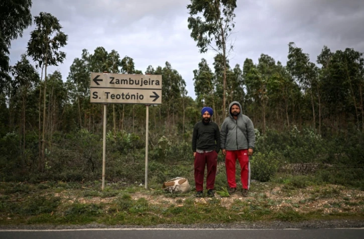 Deux immigrants indiens attendent le bus à Sao Teotonio, dans la municipalité d'Odemira au Portugal, le 16 janvier 2024