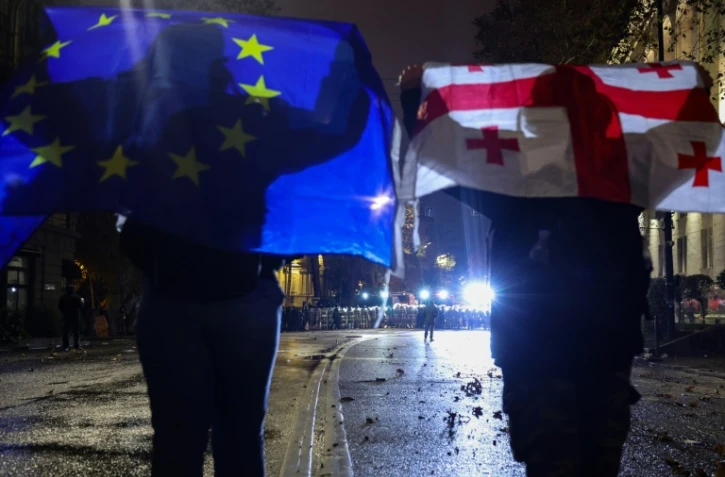 Des manifestants brandissent des drapeaux de l'Union européenne et de la Géorgie lors de la cinquième nuit consécutive de mobilisation contre le report des négociations d'adhésion à l'UE, le 3 décembre 2024 à Tbilissi, en Géorgie