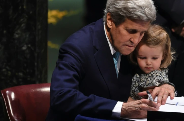 Le secrétaire d'Etat américain  John Kerry signe l'accord sur le climat, tenant sa petite-fille, le 22 avril 2016 à l'ONU à New York
