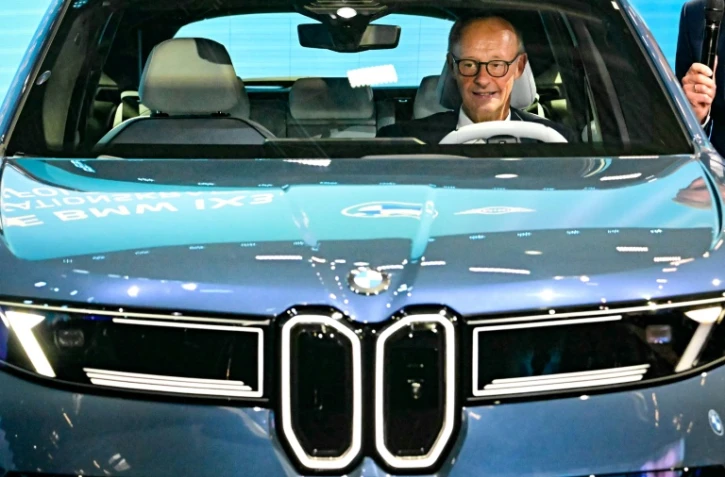 Le chancelier allemand Friedrich Merz assis dans une BMW IX3 sur le stand du constructeur automobile lors de l'ouverture du Salon international de l'automobile IAA, le 9 septembre 2025 à Munich, dans le sud de l'Allemagne