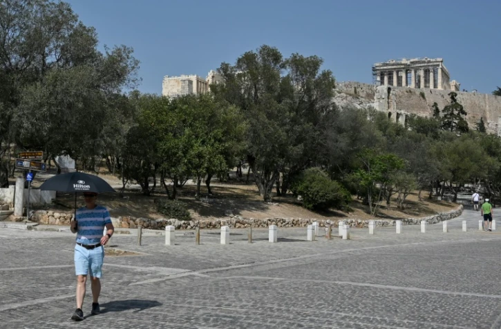 Un touriste se protège de la chaleur, au pied de l'Acropole d'Athènes, fermée aux heures les plus chaudes de la journée en raison d'une canicule exceptionnelle en Grèce, le 2 août 2021