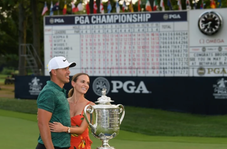 L'Américain Brooks Koepka pose avec sa compagne devant le trophée après sa victoire au Championnat PGA, dernière levée du Grand Chelem, le 12 août 2018 à St Louis (Missouri)