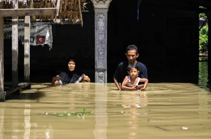 Une famille qui patauge à la sortie d'une zone résidentielle au nord d'Aceh en Indonésie, le 4 janvier 2022.