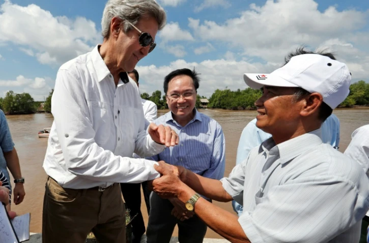 Le secrétaire d'Etat américain John Kerry sert la main de l'ancien guerillero Vo Van Tam le 14 janvier 2017 sur le delta de la rivière du Mekong