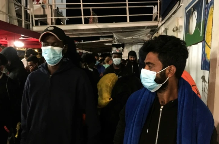 Des migrants avec des masques de protection se préparent à débarquer de l'Ocean Viking au port de Porto Empedocle, en Sicile le 6 juillet 2020