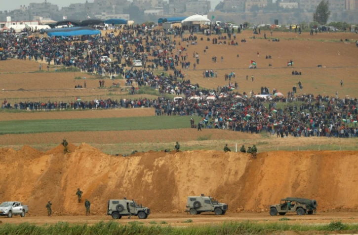 Une photo prise le 30 mars 2018 du côté israélien de la frontière, montre des Palestiniens participant à des manifestations dans la bande de Gaza, sous le regard des militaires israéliens