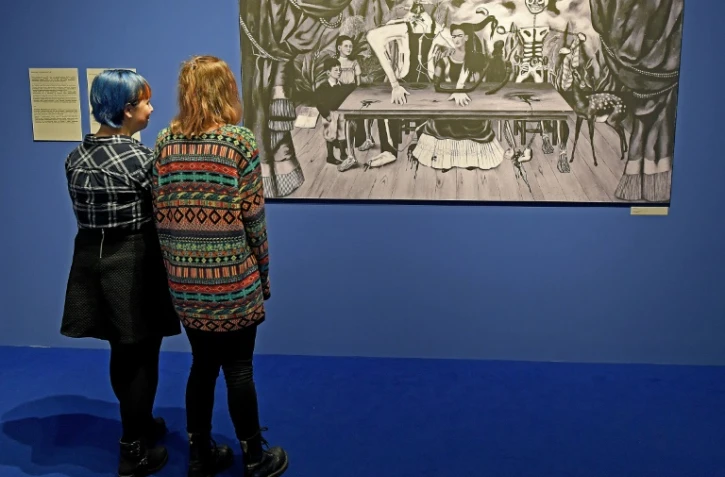 Des visiteurs d'une exposition en Pologne consacrée à Frida Kahlo et son époux contemplent une photo d'une toile disparue depuis plus d'un demi-siècle de l'artiste mexicaine, La table blessée, le 28 novembre 2017 à Poznan