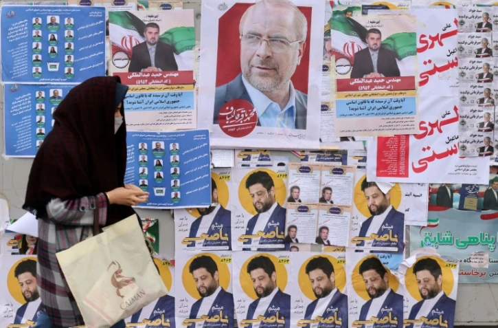 Une femme marche devant des affiches électorales placardées contre un mur de Téhéran en Iran, le 28 février 2024