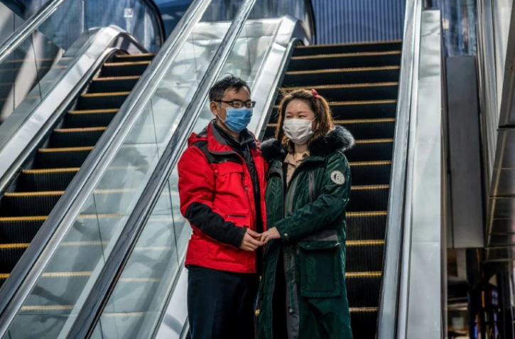 Un couple portant des masques de protection, devant un centre commercial désert, à Pékin le 22 février 2020