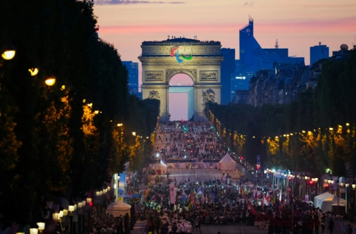 Des athlètes de différentes délégations défilent sur l'avenue des Champs-Elysées avec l'Arc de Triomphe en arrière-plan, lors de la cérémonie d'ouverture des Jeux Paralympiques de Paris 2024, à Paris, le 28 août 2024