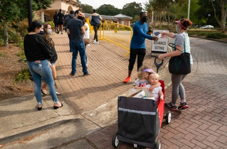 Megan Dominy avec ses deux enfants de quatre et un an, distribue de l'eau et des en-cas aux électeurs qui attendent de pouvoir déposer leurs bulletings lors du vote anticipé pour la présidentielle américaine de 2020, le 24 octobre 2020 à Smyrna