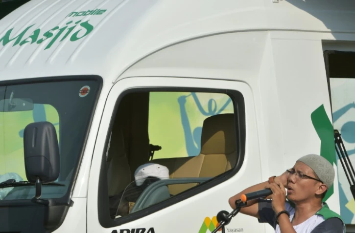 Un fidèle appelle à la prière, depuis la mosquée mobile qui sillonne les rues de Jakarta, le 28 juin 2016