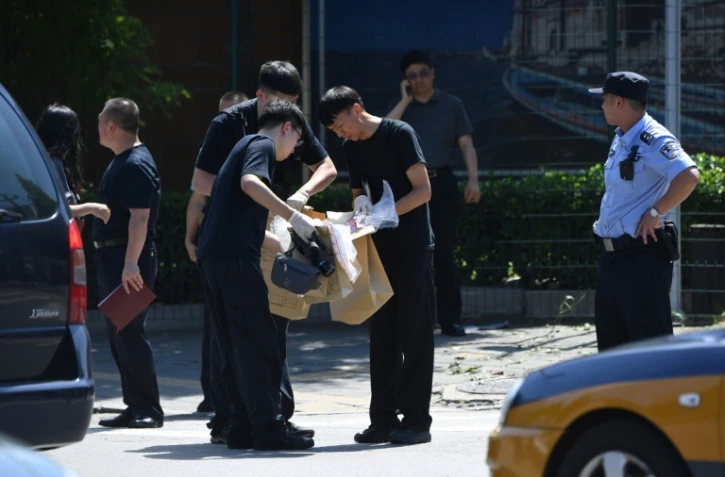 Des agents de sécurité (c) relèvent des indices après une explosion devant l'ambassade des Etats-Unis à Pékin, le 26 juillet 2018