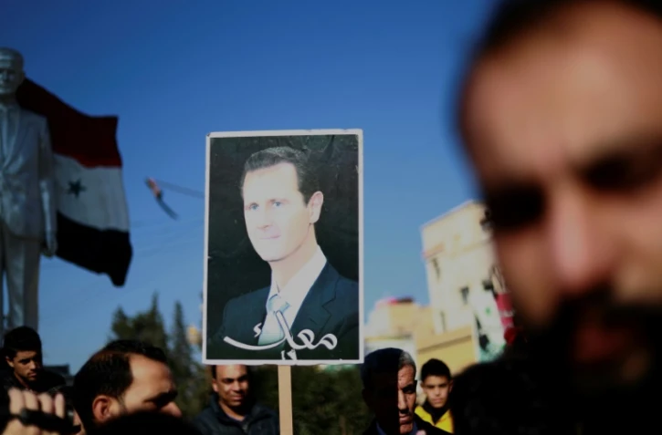Des manifestants brandissent une photo du président syrien Bachar al-Assad à Qamichli, dans le nord du pays, le 23 décembre 2018 demandant la protection de l'armée