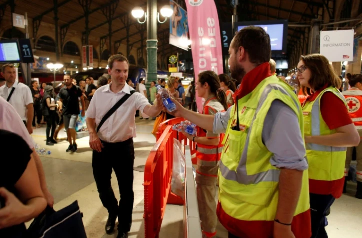 Des membres de la Croix Rouge distribuent de l'eau aux voyageurs coincés dans la soirée à la Gare du Nord, le 19 juillet 2016 à Paris