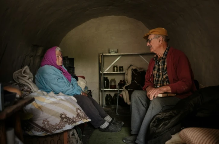 Le professeur de biologie retraité Oleksiï Poliakov (à droite), 84 ans, et sa femme Galina Poliakova, 81 ans, 81, discutent dans leur cave à légumes transformée en abri à Sydorovié, dans l'est de l'Ukraine, le 17 mai 2022