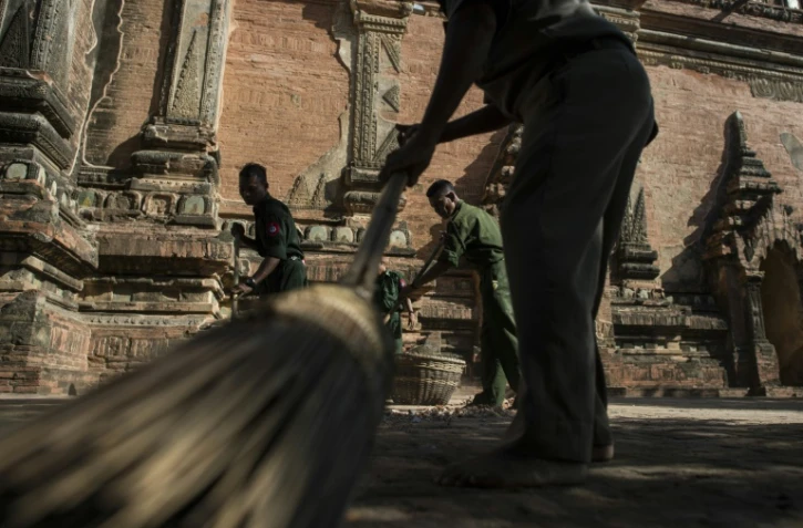 Des soldats pieds nus, comme de coutume dans les temples bouddhistes, ramassent les débris, le 25 août 2016, dans un temple du sanctuaire de Bagan endommagé la veille par un séisme