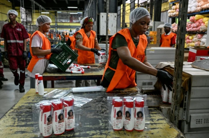 Des employées emballent des produits cosmétiques dans l'usine Kaera, située dans la zone industrielle de Yopougon, en périphérie d'Abidjan, le 7 juillet 2026 en Côte d'Ivoire