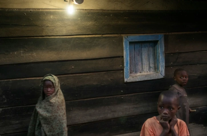 Des enfants devant une maison éclairée par l'électricité à Bugara, le 17 juillet 2016