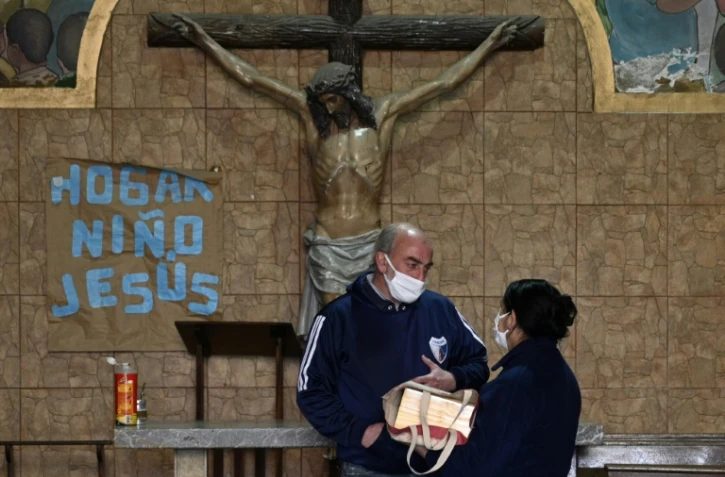 Le père Lorenzo de Vedia remet à une femme les cendres de son époux, décédé du coronavirus, le 31 juillet 2020 à Buenos Aires