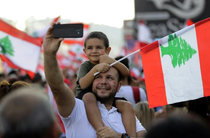 Un Libanais porte un enfant sur ses épaules, lors d'une manifestation contre le pouvoir à Zouk Mosbeh, au nord de Beyrouth, le 20 octobre 2019
