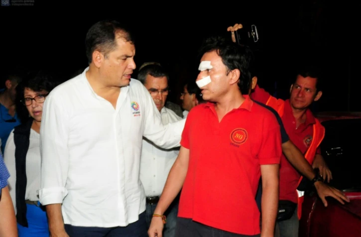 Le président d'Equateur Rafael Correa (G) s'adresse à un compatriote blessé dans le tremblement de terre dans la ville de Manta, le 17 avril 2016