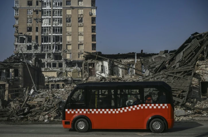 Un minibus passe devant des maisons détruites par un bombardement, le 25 mars 2022 dans un bombardement à Kharkiv, en Ukraines 2022
