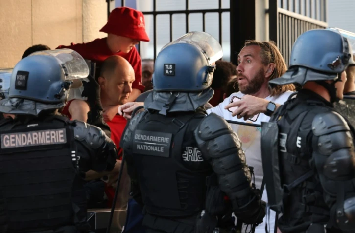 Des policiers font face à des supporters madrilènes avant le coup d'envoi de la finale de la Ligue des champions devant le Stade de France situé à Saint-Denis près de Paris, le 28 mai 2022 