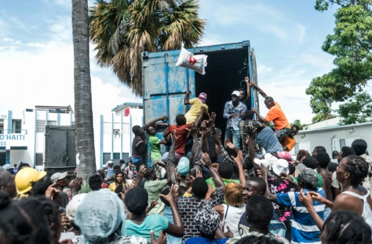 Un homme lance un sac de riz dans la foule lors d'une distribution d'aide humanitaire aux victimes du séisme du 14 août en Haïti, ici aux Cayes le 20 août 2021
